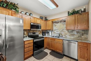 Eine moderne Küche mit Holzschränken, Edelstahlgeräten, einer gefliesten Spritzschutzwand und einem eingebauten Backofen.