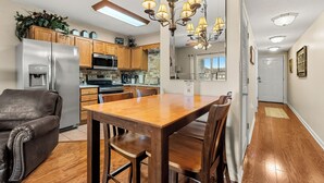 Cocina moderna con refrigerador, microondas y horno integrados. Hay una mesa de comedor con sillas y un candelabro colgante.