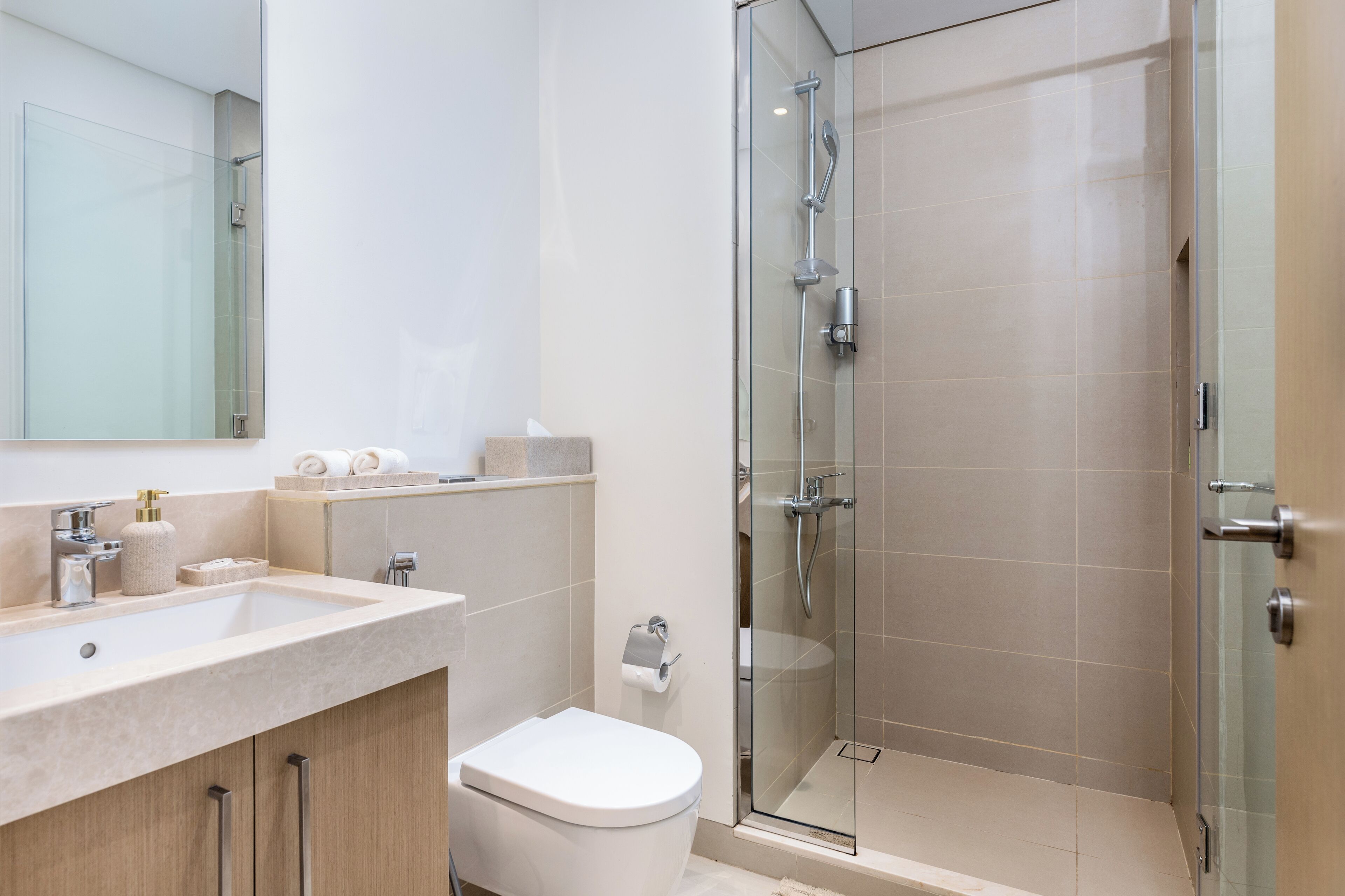 A modern bathroom with a glass-enclosed shower, a sink with a mirror, and a toilet.