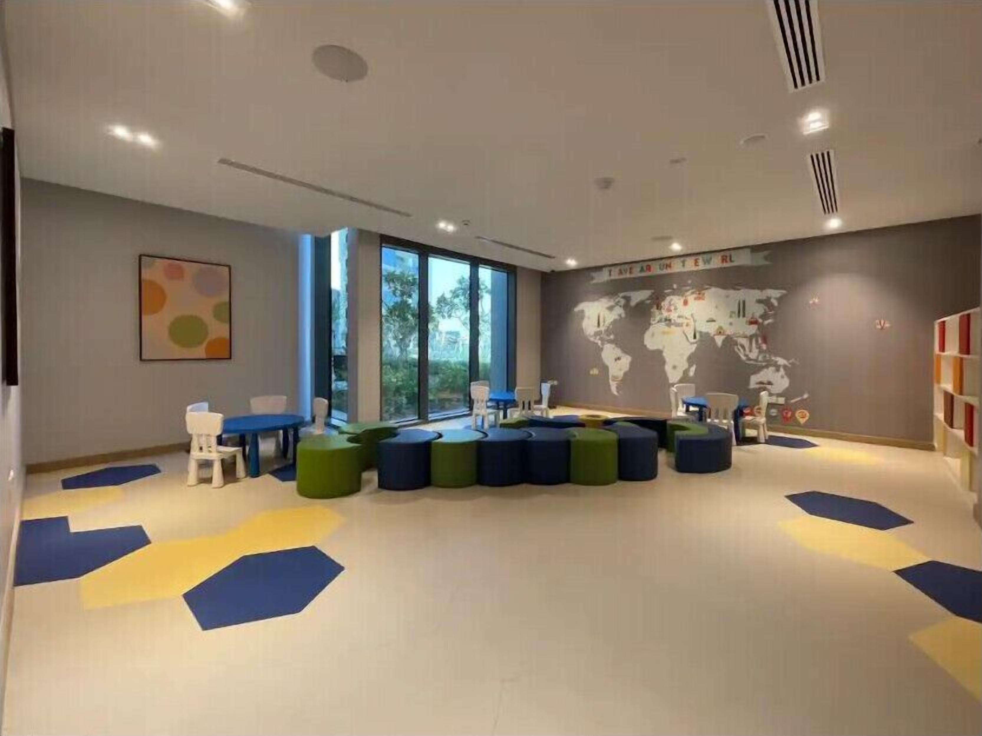 A modern children's playroom with a world map mural, colorful seating, and a large window.