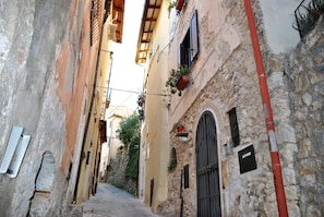 Eine enge Gasse mit alten Gebäuden, Steinmauern und einem roten Pfosten.