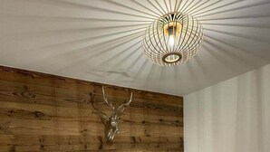 Une chambre à coucher avec une tête de lit en bois, deux lampes fixées au mur et une tête de cerf accrochée au mur.