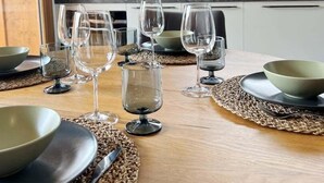 Une table à manger dressée avec des bols, des verres à vin et une bouteille.