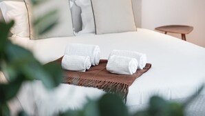 A neatly made bed with white linens and rolled towels on a brown mat. - GuestReady - Porto's Modern Comfort (Porto)
