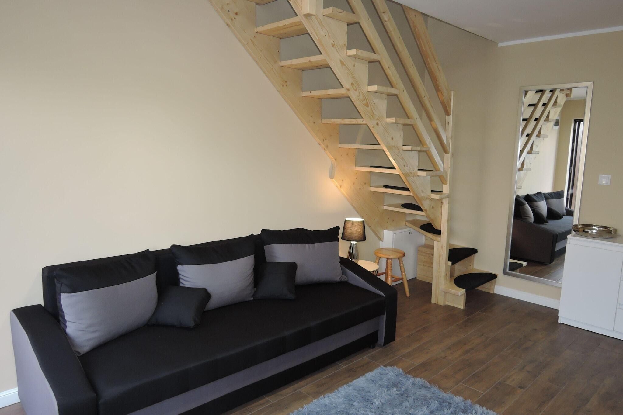 A living room with a black sofa, a wooden staircase, and a white cabinet.