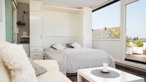 Een slaapkamer met een bed, een witte bank, een tafeltje en uitzicht op het omliggende landschap.