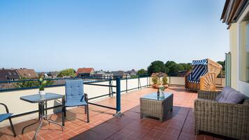 Ein Balkon mit Tisch, Stühlen und Korbmöbeln.