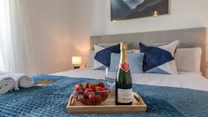 A bed with a blue blanket, a bottle of wine, and a bowl of strawberries on a tray. - Puerto Banus Serenity Retreat (Marbella)