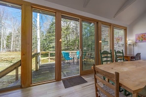 Una stanza con un tavolo di legno, sedie, una finestra e una porta che dà su una terrazza esterna.