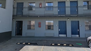 A two-story building with numbered doors, a fire extinguisher, and a visible entrance. - Motel 6 Morrilton, AR (Morrilton)