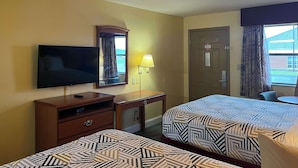 A hotel room with two beds, a TV, a desk with a lamp, a door, and a window with curtains. - Motel 6 Morrilton, AR (Morrilton)
