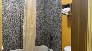A bathroom with a bathtub, a shower curtain, a toilet, and a towel rack. - Motel 6 Morrilton, AR (Morrilton)