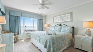 A bedroom with a bed, a desk, a chair, a nightstand, and a ceiling fan. - Oceanfront Delight - Indoor Pool, Sleeps 4 (North Myrtle Beach)