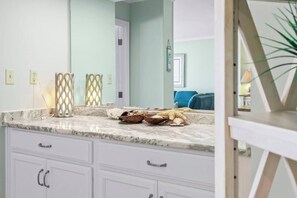 A bathroom with a marble countertop, white cabinetry, and a mirror. - Oceanfront Delight - Indoor Pool, Sleeps 4 (North Myrtle Beach)