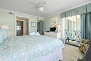Une chambre d’hôtel équipée d’un lit, d’une télévision, d’un bureau, d’une chaise, d’un balcon avec vue et d’un ventilateur de plafond.