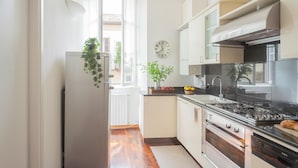 A modern kitchen with white cabinets, a black stove, and a clock on the wall. - Filanda - Best Lakefront in Como (Como)