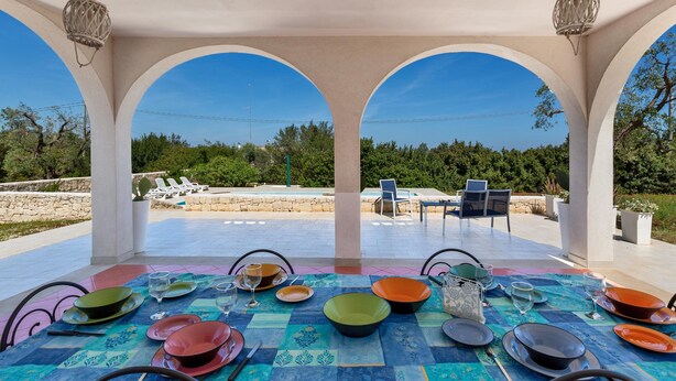 An outdoor dining area with a view of a pool and greenery. - 3880 Villa Sierri by Perle di Puglia (Carovigno)