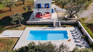 A modern villa with a swimming pool, outdoor seating, and a view of olive groves. - 3880 Villa Sierri by Perle di Puglia (Carovigno)