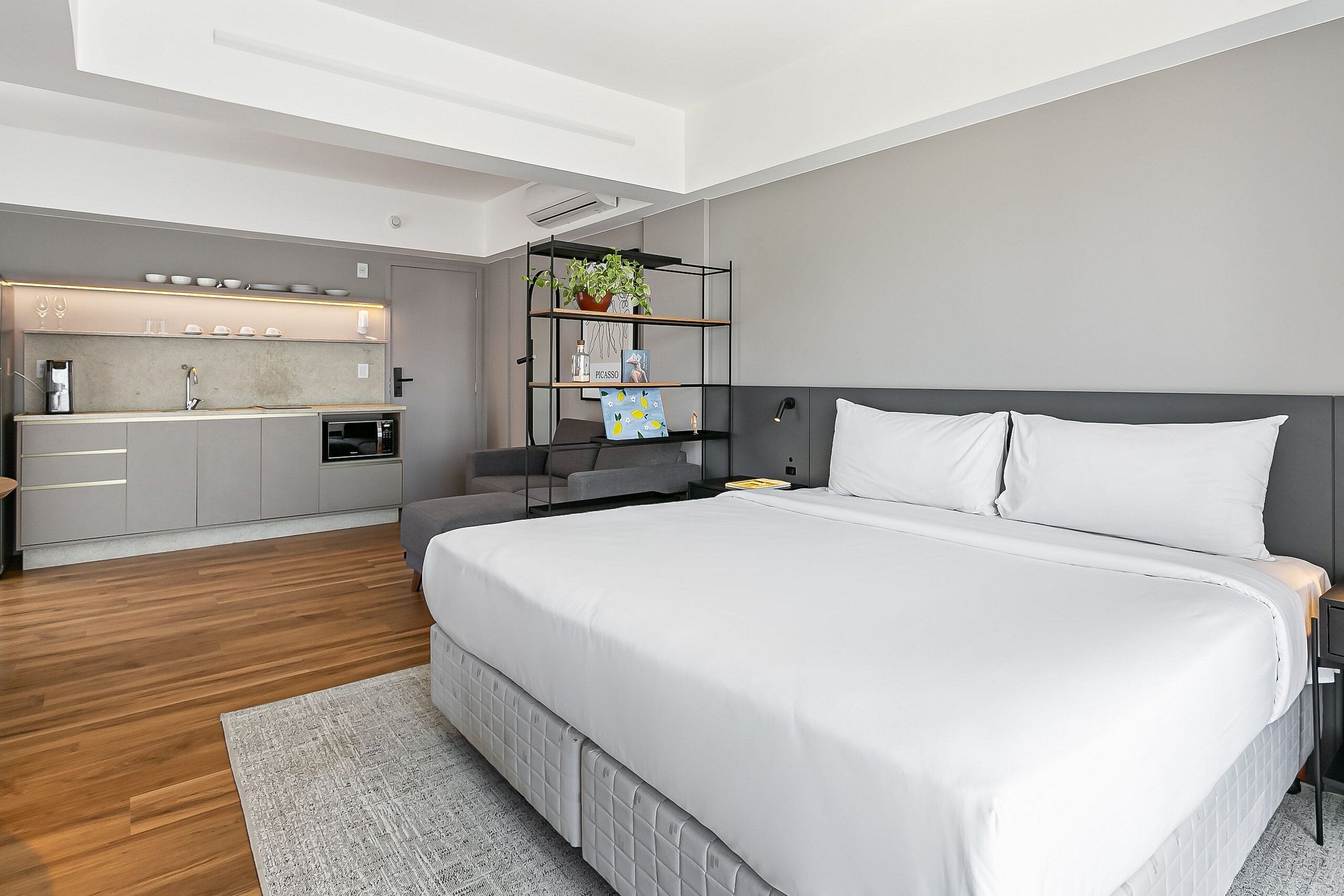A modern bedroom with a large bed, a bedside table, a nightstand, and a built-in wardrobe.
