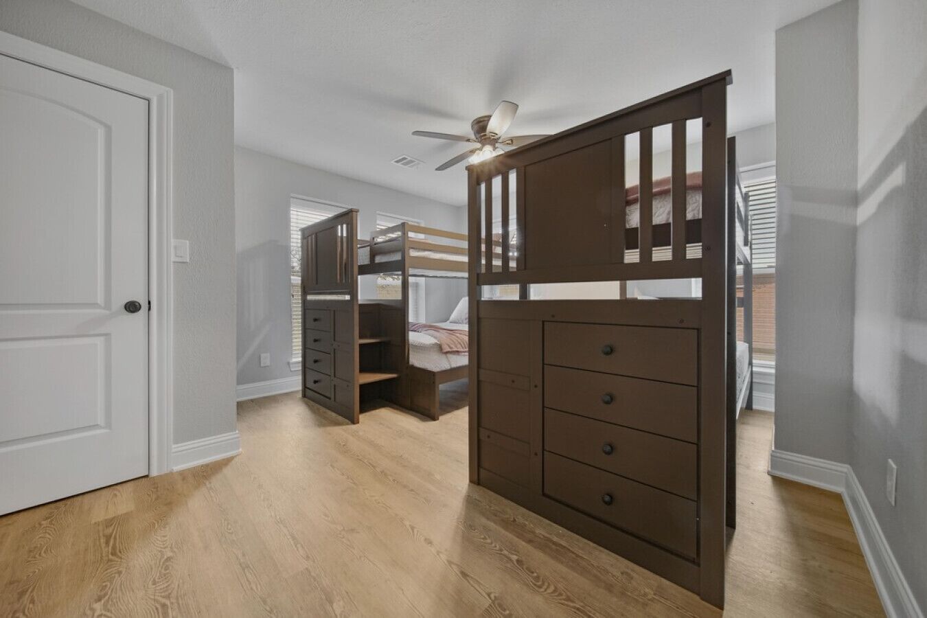 Una habitación con literas, un aparador de madera y un ventilador de techo.