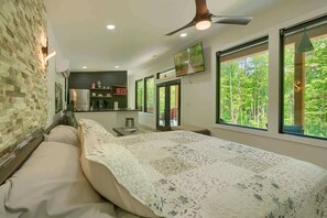 Une chambre dotée d’un grand lit, offrant une vue sur l’extérieur, d’un coin cuisine et d’un ventilateur de plafond.
