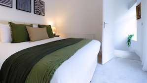 A bedroom with a bed, bedside tables, a nightstand, and wall art. - 3 Bed Home near Hiking Trails & Parks (Rhondda)