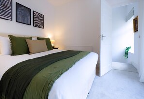 A bedroom with a bed, bedside tables, a nightstand, and wall art. - 3 Bed Home near Hiking Trails & Parks (Rhondda)