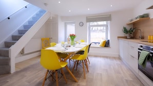 A modern kitchen with a dining area, wooden flooring, and a staircase. - 3 Bed Home near Hiking Trails & Parks (Rhondda)