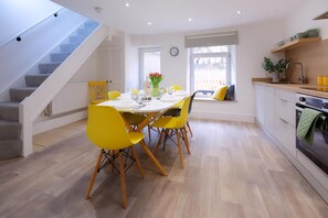 A modern kitchen with a dining area, wooden flooring, and a staircase. - 3 Bed Home near Hiking Trails & Parks (Rhondda)