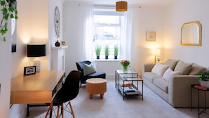 A modern living room with a dining area, a sofa, a coffee table, and a window with plants. - 3 Bed Home near Hiking Trails & Parks (Rhondda)