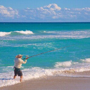 Iemand vist op een strand met helder turquoise water en een rustige zee.