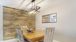 Un espace repas avec un mur en bois, une table à manger en bois et des chaises.