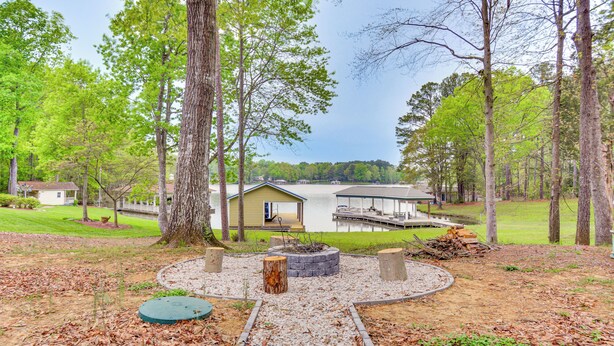 Un chalet au bord du lac, doté d’un quai, entouré d’arbres et comprenant un espace aménagé avec un foyer.