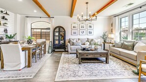 A spacious living room with a wooden ceiling, a chandelier, a sofa, a coffee table, and a dining area with chairs and a table. - Enchanting Clovis Haven w/ Hot Tub & Private Pool! (Clovis)