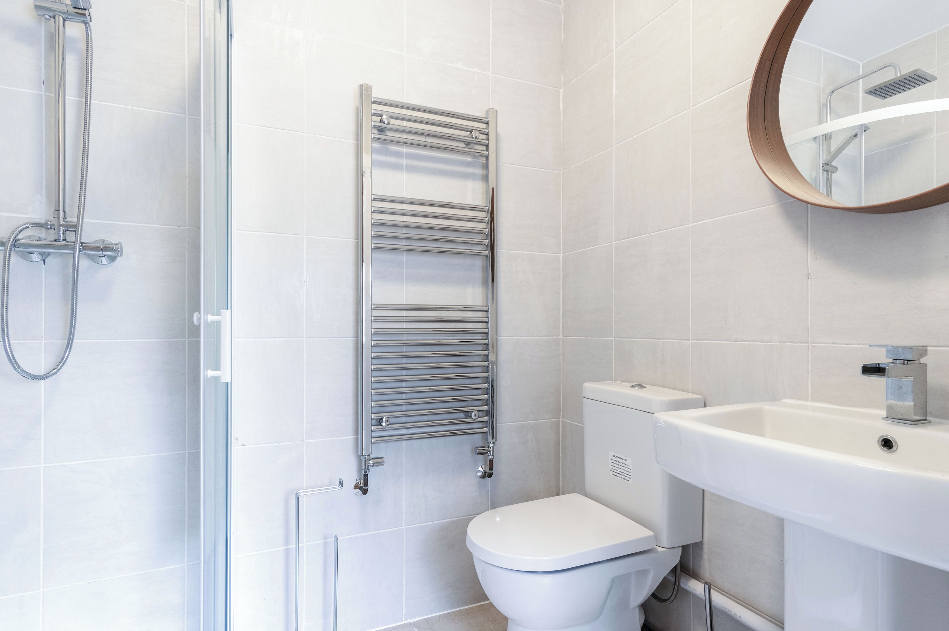 Un bagno moderno con cabina doccia in vetro, portasci in cromo, vaso sanitario bianco e lavandino con specchio sopra.