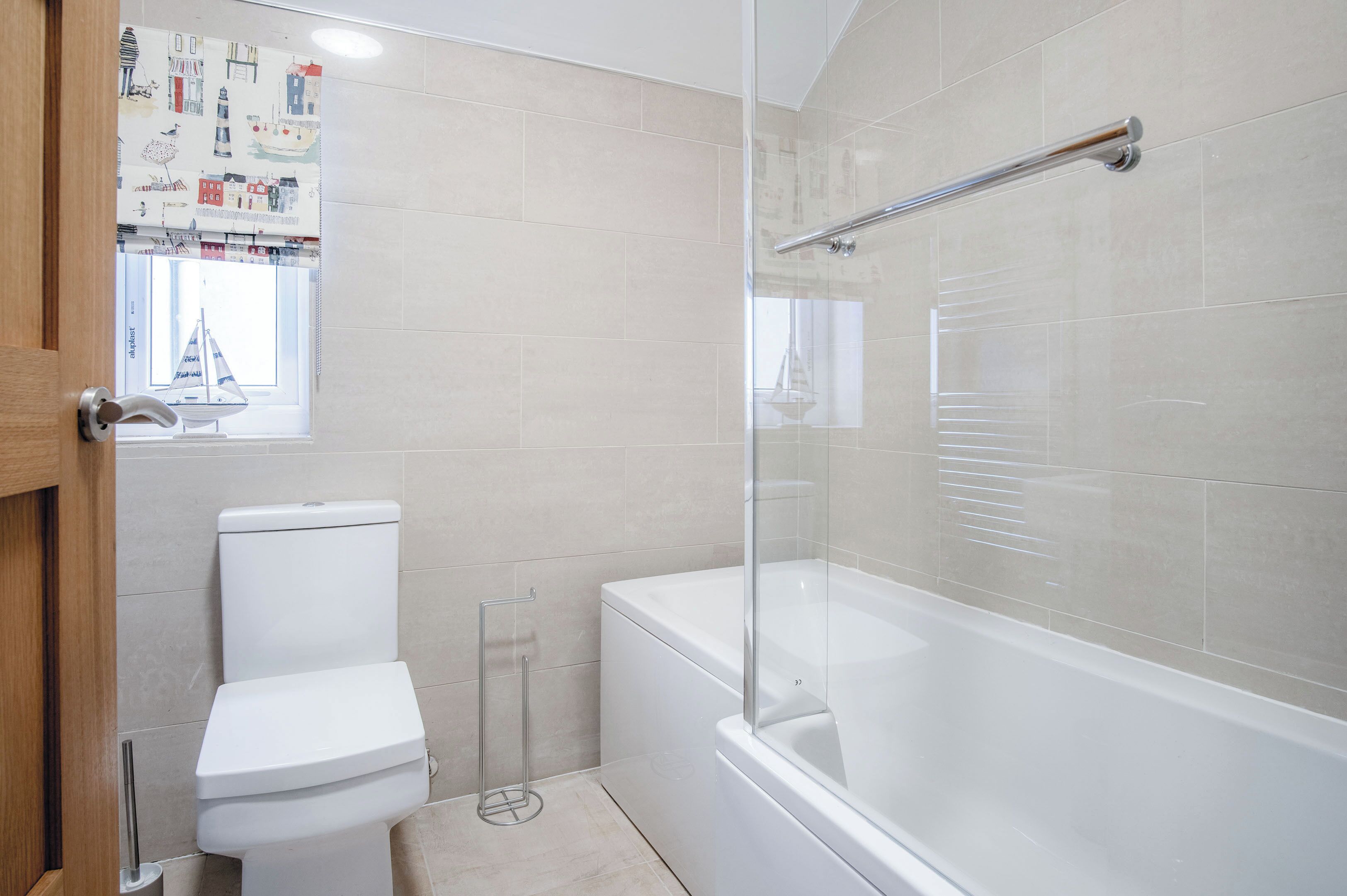 Een moderne badkamer met een toilet, een douchecabine en een bad.