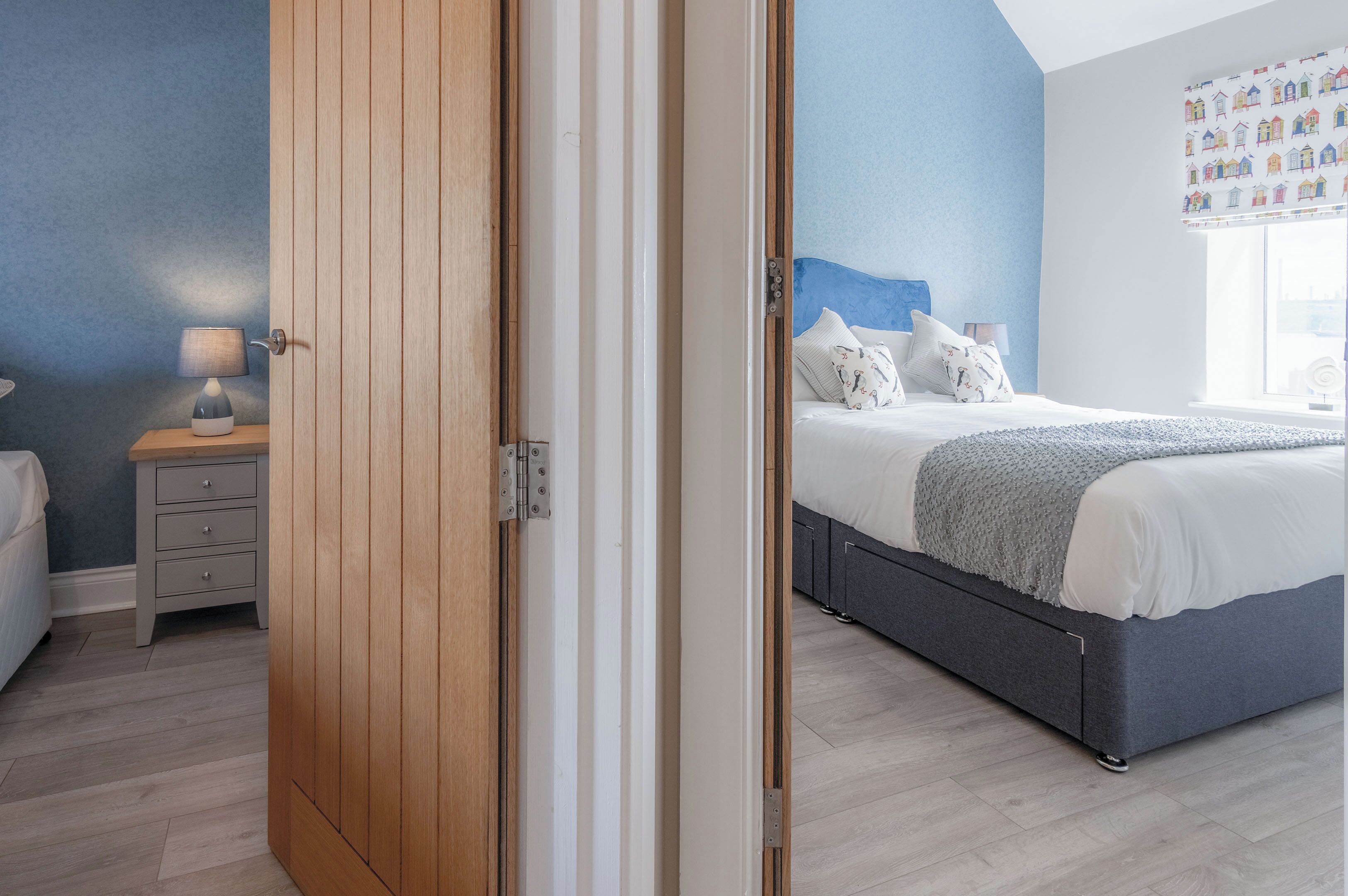 A bedroom with a bed, a nightstand, and a wooden wardrobe.