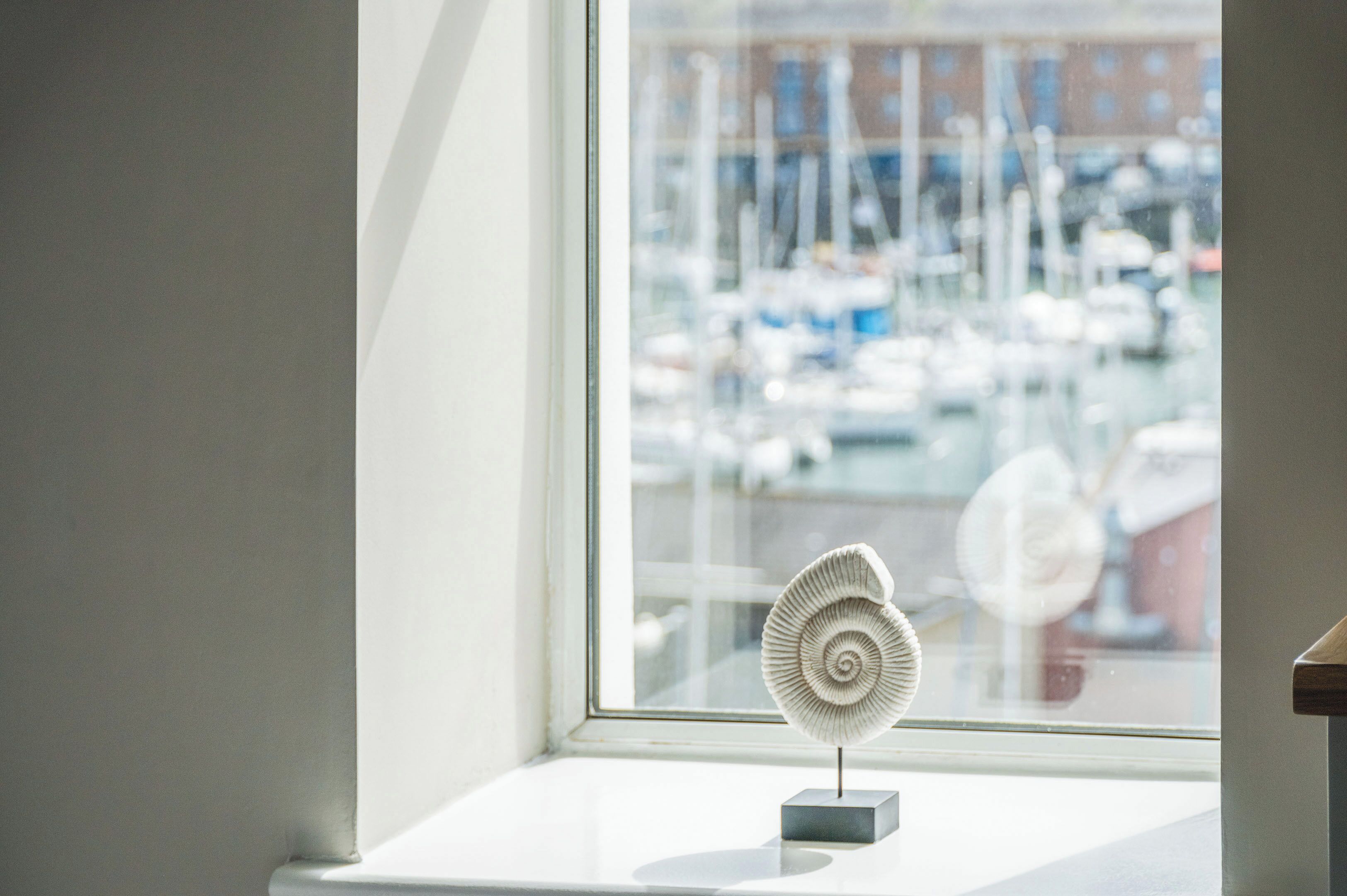 A fan on a windowsill with a marina view.