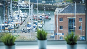 A marina with boats docked, a brick building, and potted plants in the foreground. - Beach Haven Hideout - 2 Bedroom - Milford Haven (Milford Haven)
