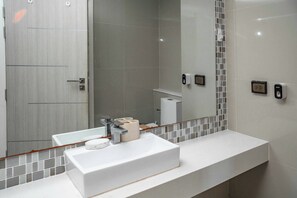 A modern bathroom with a white sink, a mirror, and a toilet. - One Tower apartments by Apartwell (Pattaya)