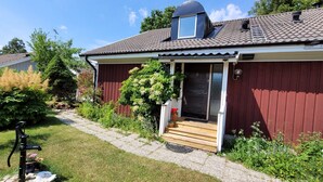 Une maison en bois rouge avec un petit porche, une fenêtre et une cheminée.