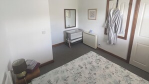 Een slaapkamer met een bed, nachtkastje, radiator, spiegel en een deur.