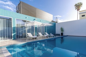 A modern pool area with clear blue tiles, white lounge chairs, and umbrellas. - 2M BOUTIQUE HOTEL (Montijo)