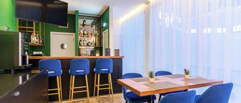 Una cucina moderna con un'area bar, sgabelli azzurri e un tavolo da pranzo con sedie blu.