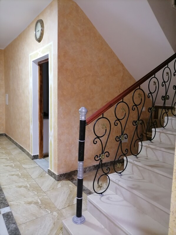 Una escalera con barandilla metálica y un bolardo negro y plateado.