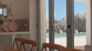 Vue depuis une chambre dotée d’une porte-fenêtre coulissante donnant sur un espace piscine extérieur.