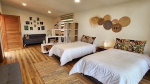 Une chambre avec deux lits, un plancher en bois, un canapé, une bibliothèque et des éléments décoratifs sur les murs.