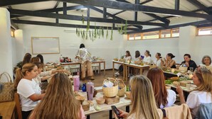 Un groupe de personnes est assis à des tables dans une pièce rustique aux poutres apparentes, et participe à un repas ou à une activité.