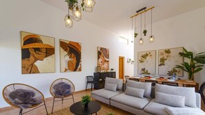 A modern living room with a grey sectional sofa, two chairs, a coffee table, and artwork on the walls. - Villa Humaik by Villa Plus (Antigua)