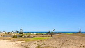 A golf course with a clear view of the ocean and distant buildings. - Villa Humaik by Villa Plus (Antigua)